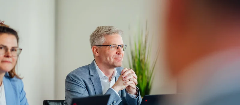 Mehrere Personen sitzen mit Laptops in einem Besprechungsraum und hören einander zu. Das Bild steht für Personalberatung, Personalmanagement sowie Führungs- und Personalarbeit beim Genossenschaftsverband Weser-Ems.