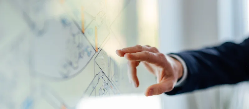 Eine Hand zeigt auf eine digitale Darstellung mit Linien und Markierungen. Das Bild steht für strategische Unternehmensberatung und Orientierung für Genossenschaftsbanken in Weser-Ems.