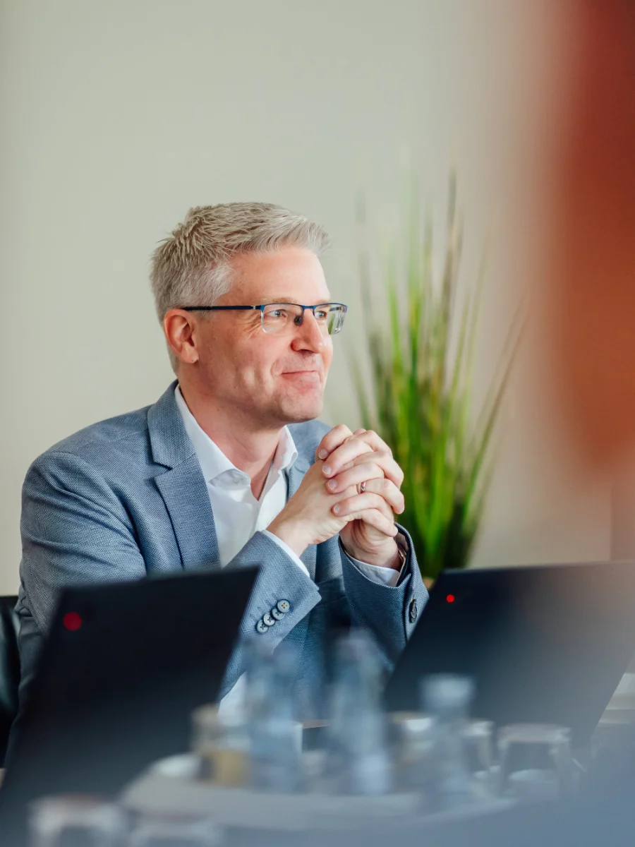Mehrere Personen sitzen mit Laptops in einem Besprechungsraum und hören einander zu. Das Bild steht für Personalberatung, Personalmanagement sowie Führungs- und Personalarbeit beim Genossenschaftsverband Weser-Ems.
