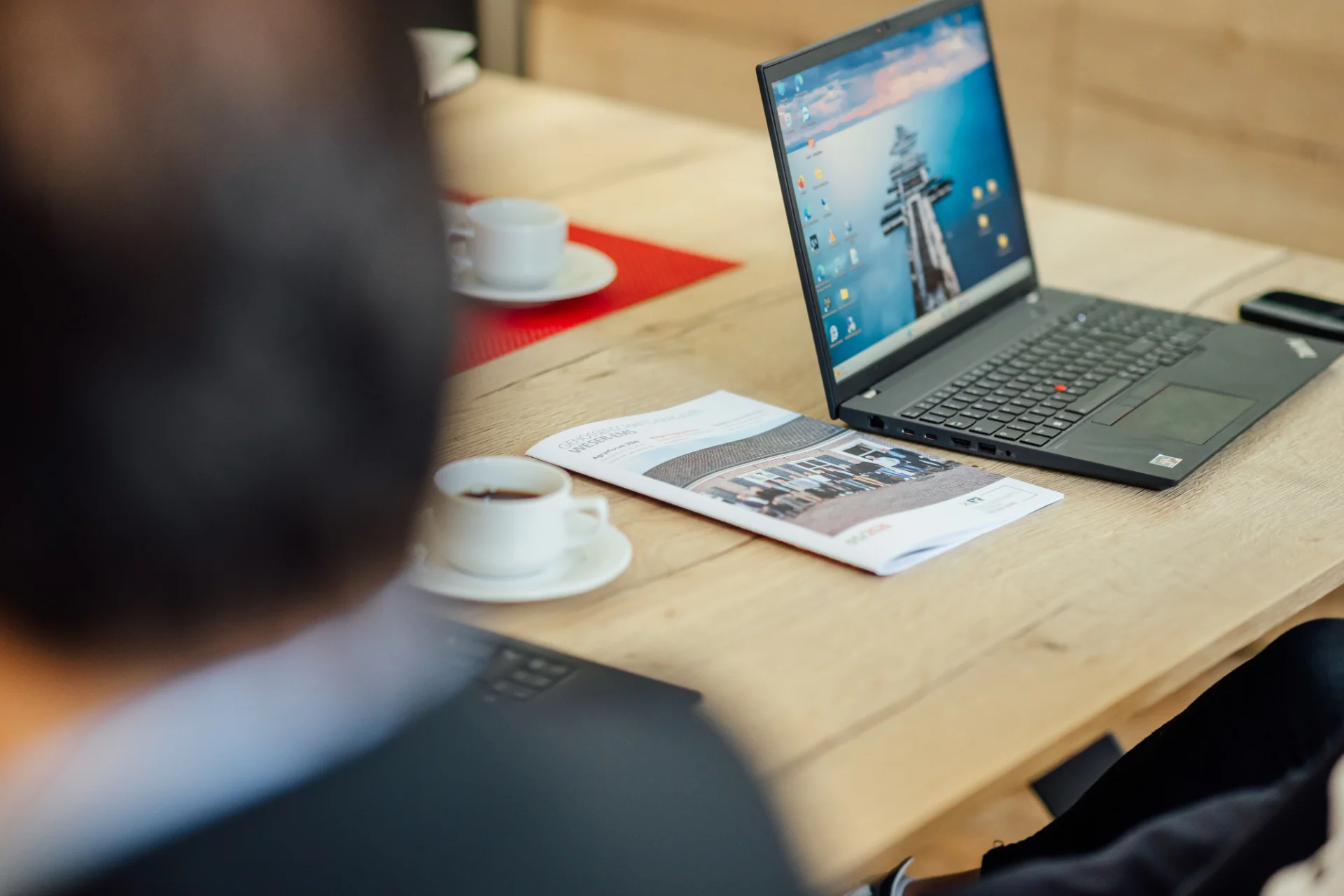 Ein geöffneter Laptop, eine GVWE-Broschüre und Kaffeetassen liegen auf einem Besprechungstisch. Das Bild steht für persönliche Gründungsberatung und die fachliche Begleitung beim Aufbau einer Genossenschaft.