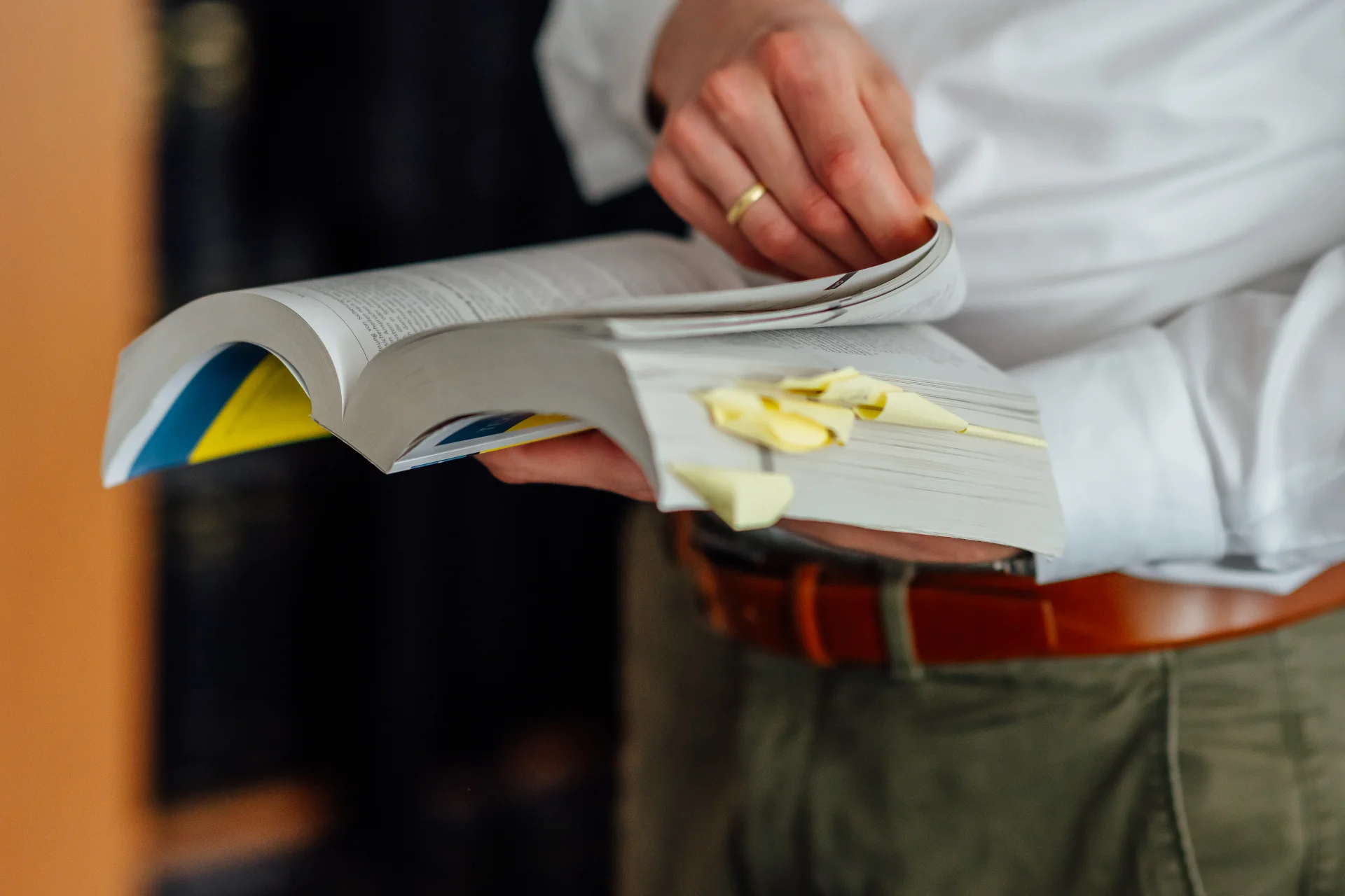 Eine Person blättert in einem mit Haftnotizen markierten Fachbuch. Das Bild steht für sorgfältige rechtliche Prüfung und Rechtsberatung beim Genossenschaftsverband Weser-Ems.
