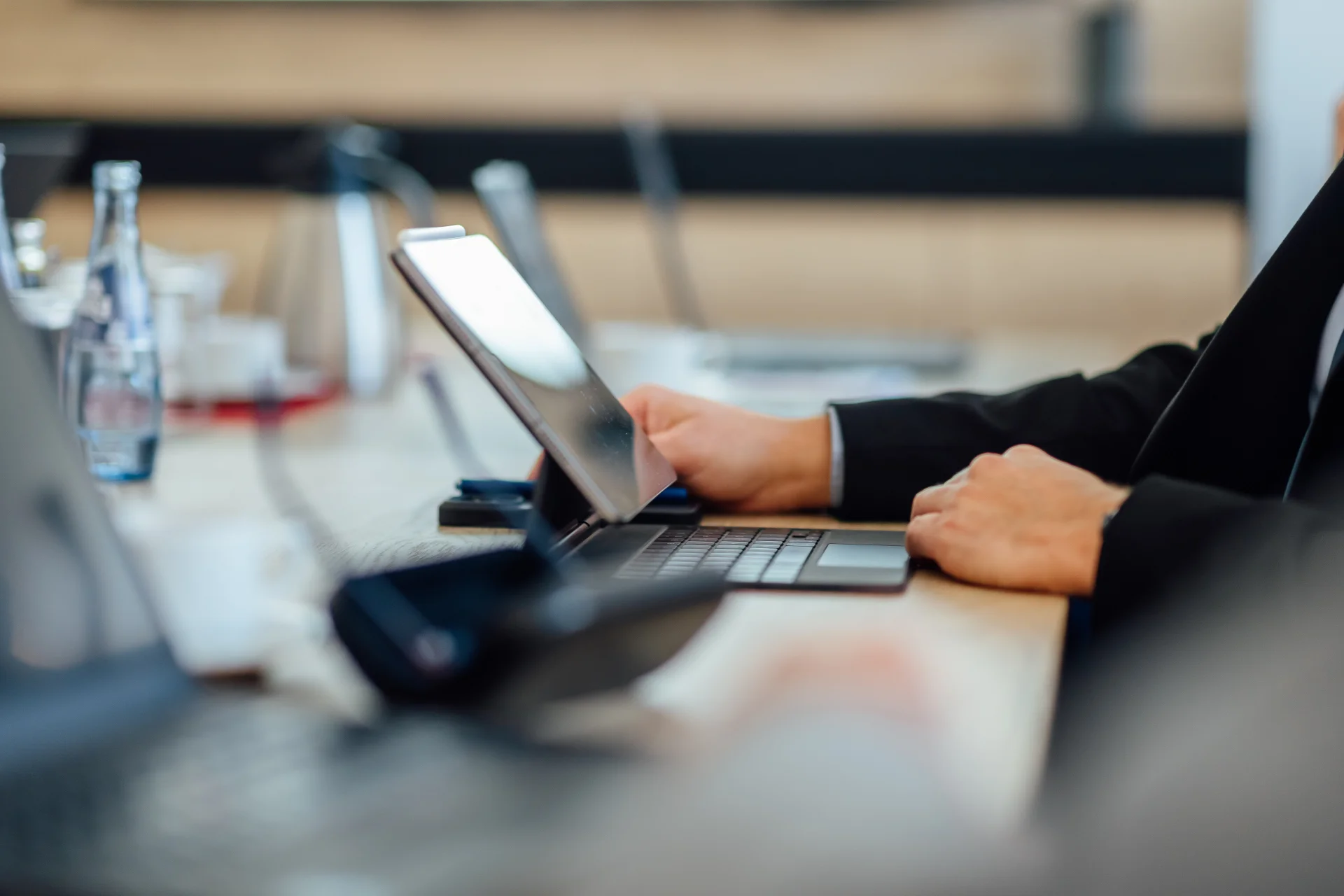 Eine Person in Geschäftskleidung arbeitet in einem Besprechungsraum an einem Tablet mit Tastatur. Das Bild steht für fundierte Unternehmensberatung zu strategischen Fragen und unternehmerischen Entscheidungen.